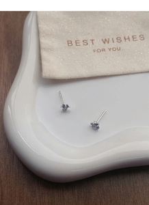 Vue détaillée des boucles d'oreilles iris bleu en argent S999 sur plateau céramique