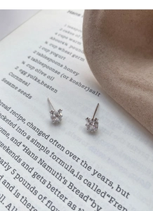 Vue macro de boucles d'oreilles étoile en argent S999 avec pierres sur une page de livre