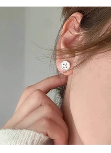 Detailed close-up of S999 sterling silver button stud earrings on a female model's ear