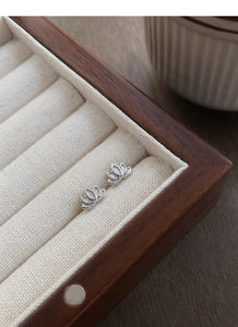 Close-up of S999 sterling silver lotus stud earrings in a burlap jewelry display box