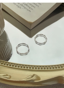 Close-up of S999 sterling silver bamboo joint rings reflecting on a polished mirror surface