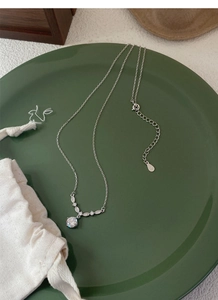 Détail du collier fleur en argent S999 avec goutte en zircon sur plat en céramique