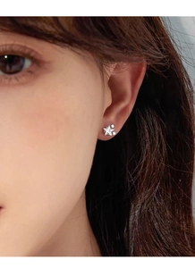 Gros plan de boucles d'oreilles étoiles en argent sterling avec zircons sur l'oreille