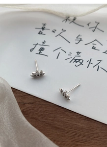 Macro shot of minimalist S999 silver lotus stud earrings with polished petals on card
