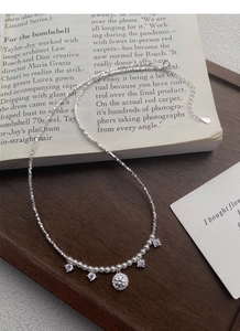Détail d'un collier en argent S925 avec perles et breloques en zircon sur fond de livre