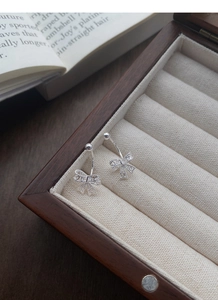 Détails de boucles d'oreilles nœud en argent avec motif dentelle dans une boîte en bois