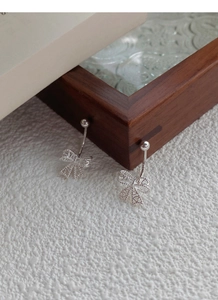 Détail des boucles d'oreilles nœud en argent creux avec motifs de cœur sur bois