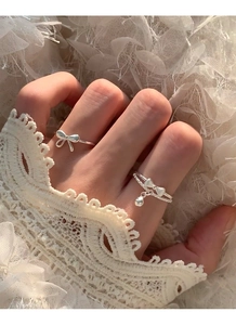 Detail of silver S925 layered bow ring with tiny bell charm on woman's hand