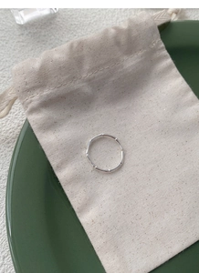 Macro detail of silver bamboo joint ring on linen pouch with green ceramic background