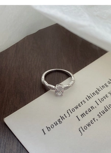 Macro shot of a S925 silver ring featuring an oval-cut zircon stone on vintage paper