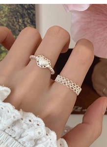 Détail de bagues en argent S925 avec motifs de dentelle et de cœur portées par un mannequin