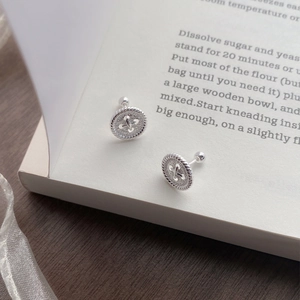S999 sterling silver button stud earrings with rope border and screw back on a vintage book