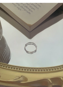 Detailed view of S999 silver bamboo joint ring on a vintage mirror surface background
