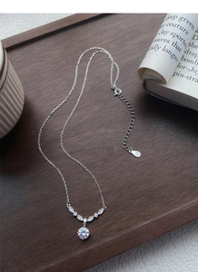 Détail du collier en argent S925 avec pendentif en zircon blanc sur plateau bois