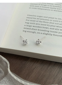 Détail macro de boucles d'oreilles en zircon carré avec griffes en forme d'étoile