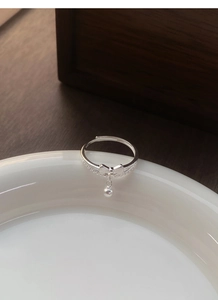 Detailed macro view of S925 silver bow ring with hanging bead and zircon inlay