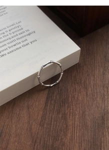 Macro detail of the bamboo-shaped silver ring texture on a book and wooden background