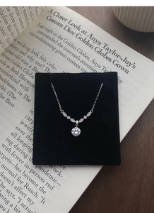 Détail macro du collier fleur en argent S999 avec zircon goutte sur présentoir en velours