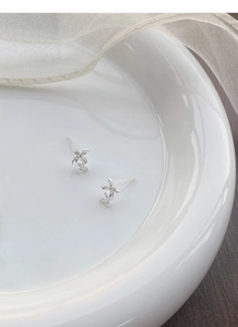 Detailed view of S999 silver osmanthus flower stud earrings on a white ceramic plate