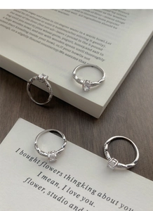 Detailed close-up of S925 silver rings with oval zircon gemstones on vintage book pages