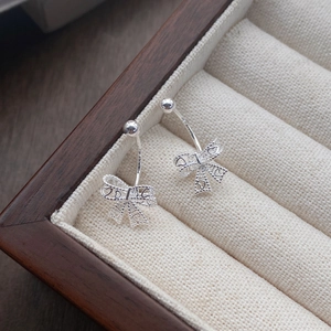 Boucles d'oreilles nœud en argent S999 avec motifs cœurs sur un coffret à bijoux haut de gamme