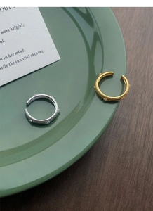 Macro detail of textured silver and gold adjustable rings on a green ceramic plate