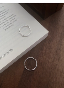 Macro detail of two silver bamboo joint rings placed on a book and wooden surface