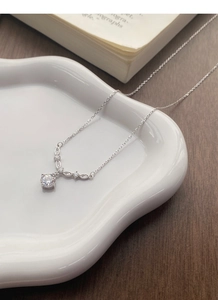Gros plan d'un collier fleur en argent avec zircon sur un plateau en céramique chic