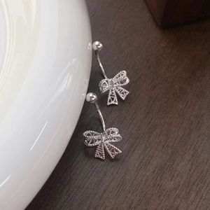 Élégantes boucles d'oreilles nœud creux en argent S999 sur une assiette en céramique