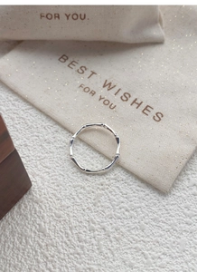 Detailed macro shot of a bamboo-style silver ring on a white textured stone surface