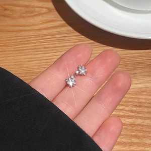 Boucles d'oreilles étoiles en argent S999 avec zircons sur une table en bois rustique