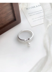 Detailed shot of S925 sterling silver bow ring with polished bead charm and textured band