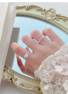 Détail de bagues en argent avec forme de coeur et anneau tissé sur doigt