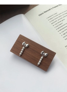 Detailed macro view of S925 silver bow earrings featuring elegant faux pearl tassels
