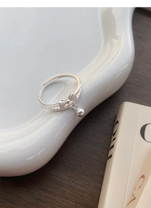 Macro view of S925 sterling silver bow ring featuring a delicate small bell pendant