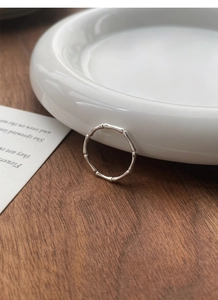 Macro view of S999 sterling silver bamboo joint ring on white ceramic and wooden background