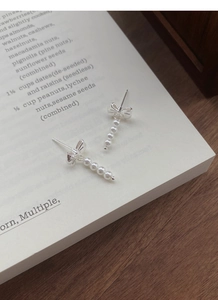 Detail of silver S925 bowknot earrings with white pearl tassels on an elegant book