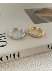 Detail of adjustable silver and gold rings with vertical stripe texture and zircon stones