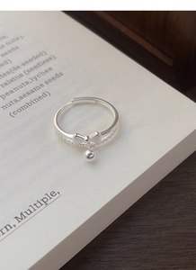 Detail shot of a S925 sterling silver bow ring with a swinging bead on an open book