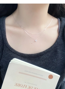 Detail of elegant double-layer S925 silver necklace with a sparkling round solitaire pendant