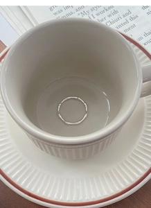Detailed view of an S999 sterling silver bamboo joint ring placed inside a white ceramic cup