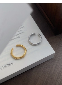 Detail of gold and silver C-shaped rings with woven texture on a white book