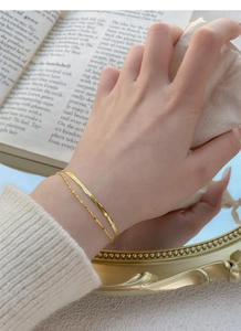 Détail d'un bracelet double chaîne serpent dorée porté au poignet pour un look élégant