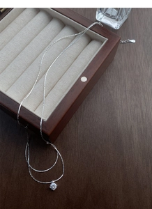Detailed view of S925 sterling silver solitaire necklace on a vintage wooden box