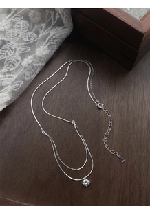 Detail of S925 sterling silver double layer necklace with S925 hallmark on a wooden surface