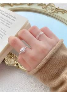 Gros plan sur bague en argent S925 dentelle et cœur portées à la main, style vintage chic