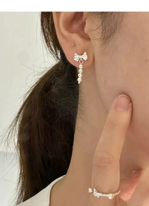 Detail view of S925 silver bow earrings with imitation pearls and matching butterfly ring