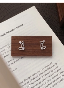 Close-up of S999 sterling silver heart stud earrings with cubic zirconia on wood