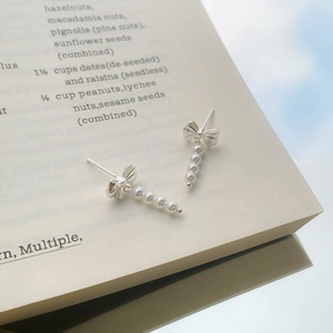 Elegant S925 silver bow earrings with faux pearl tassels displayed on a vintage book