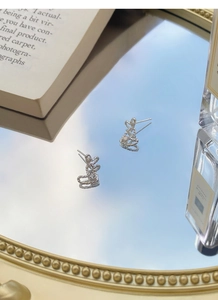 Close-up of S999 sterling silver heart stud earrings with hammered texture on a mirror